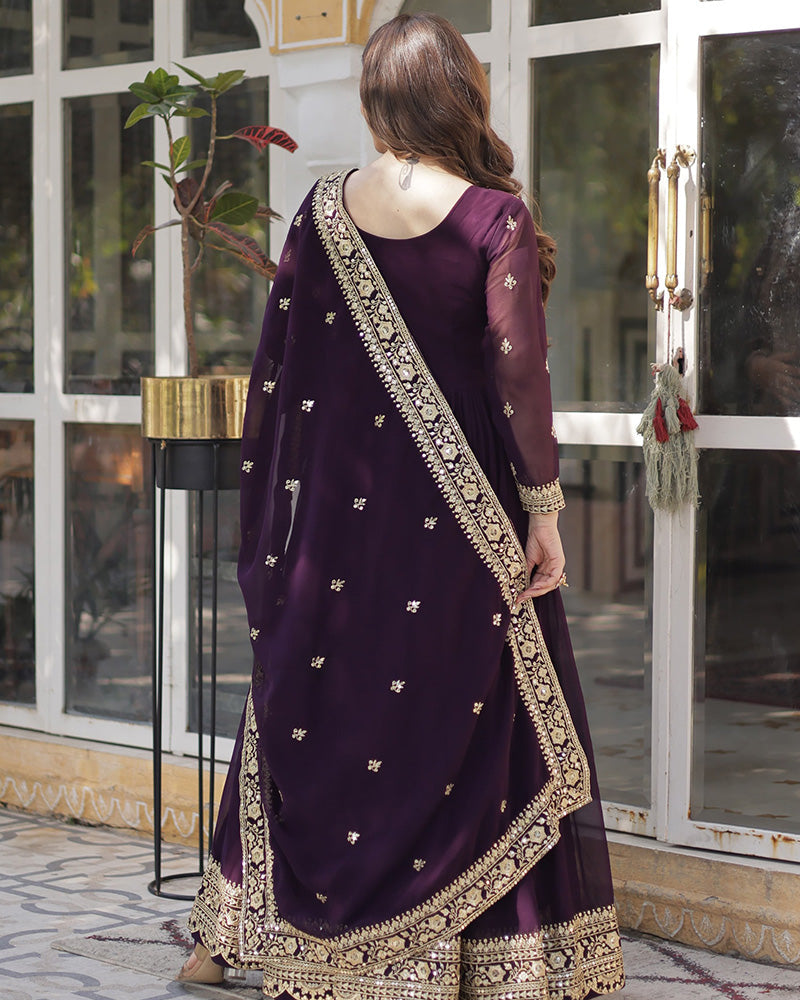 Woman wearing a purple traditional outfit with gold embroidery in an outdoor setting.