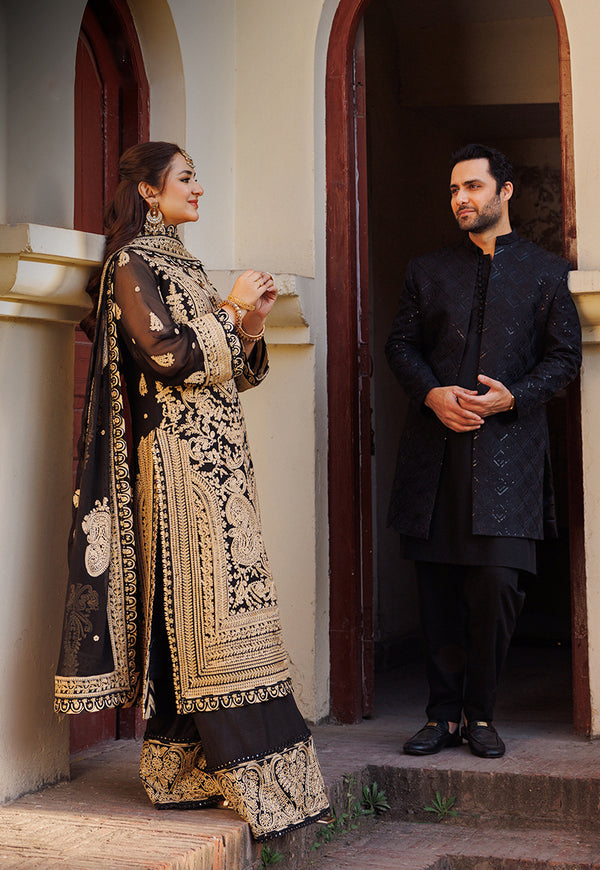 Man and woman in traditional attire standing in a doorway.