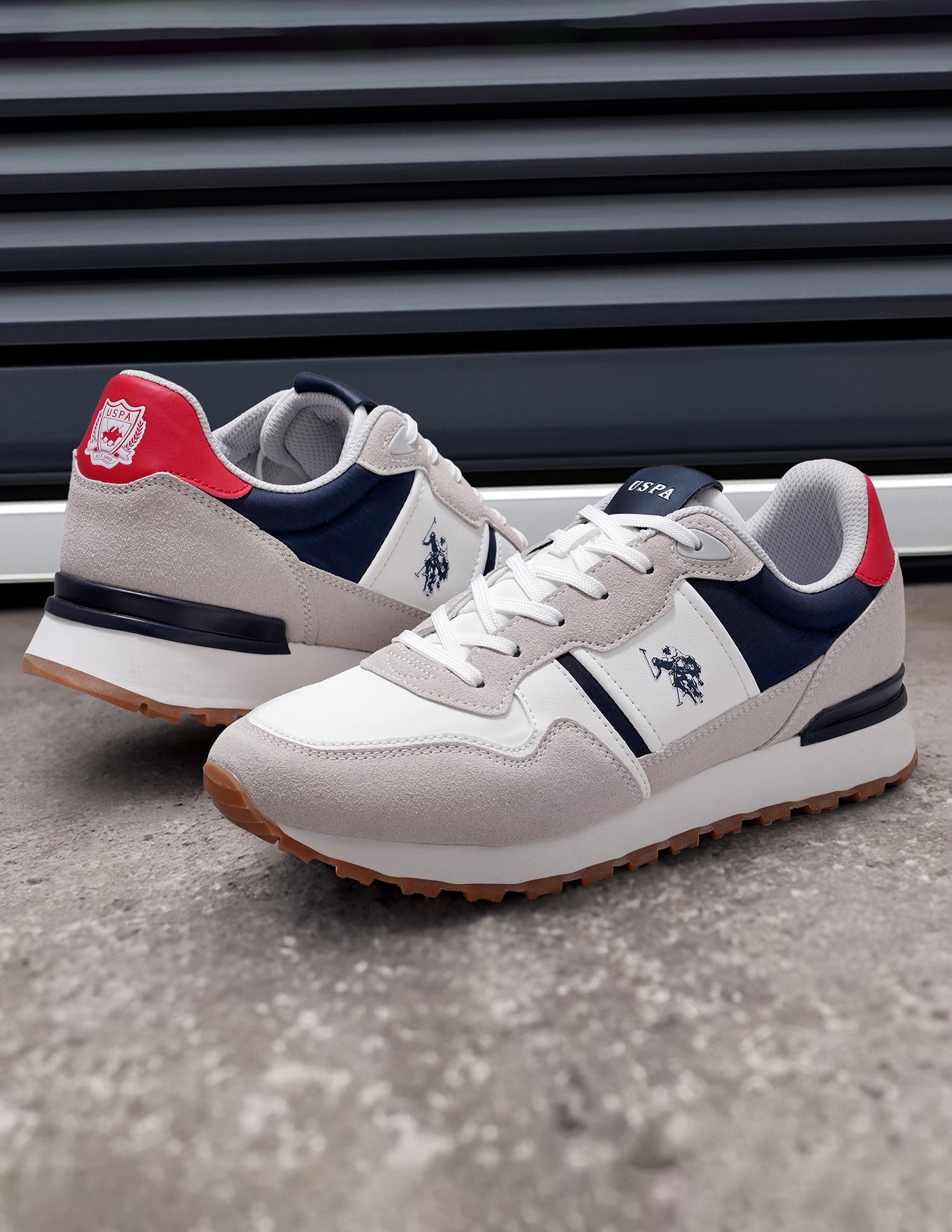 Pair of sneakers with red, white, and blue design on a concrete floor.