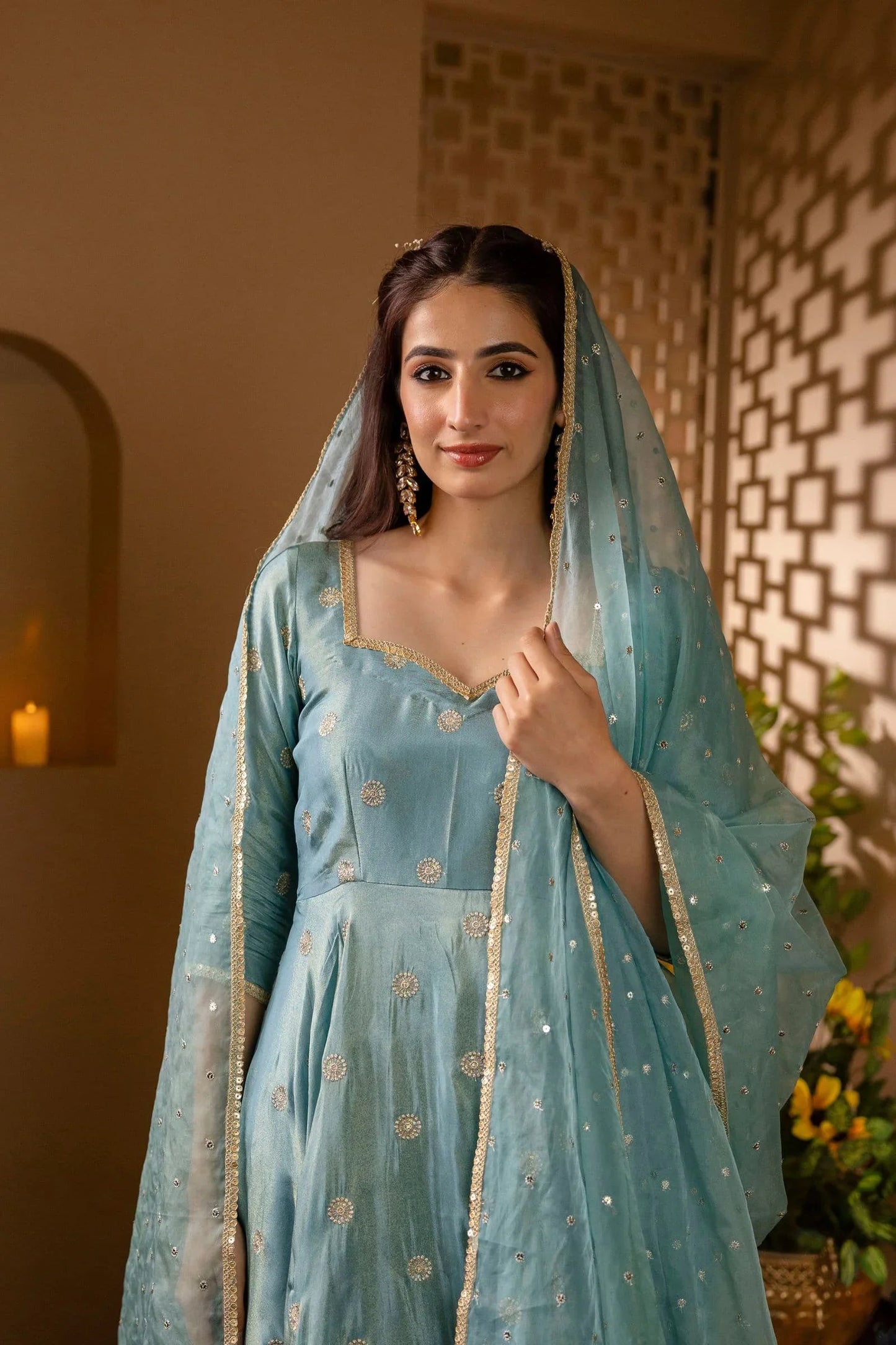 Woman in a light blue traditional outfit with a matching dupatta, standing indoors.