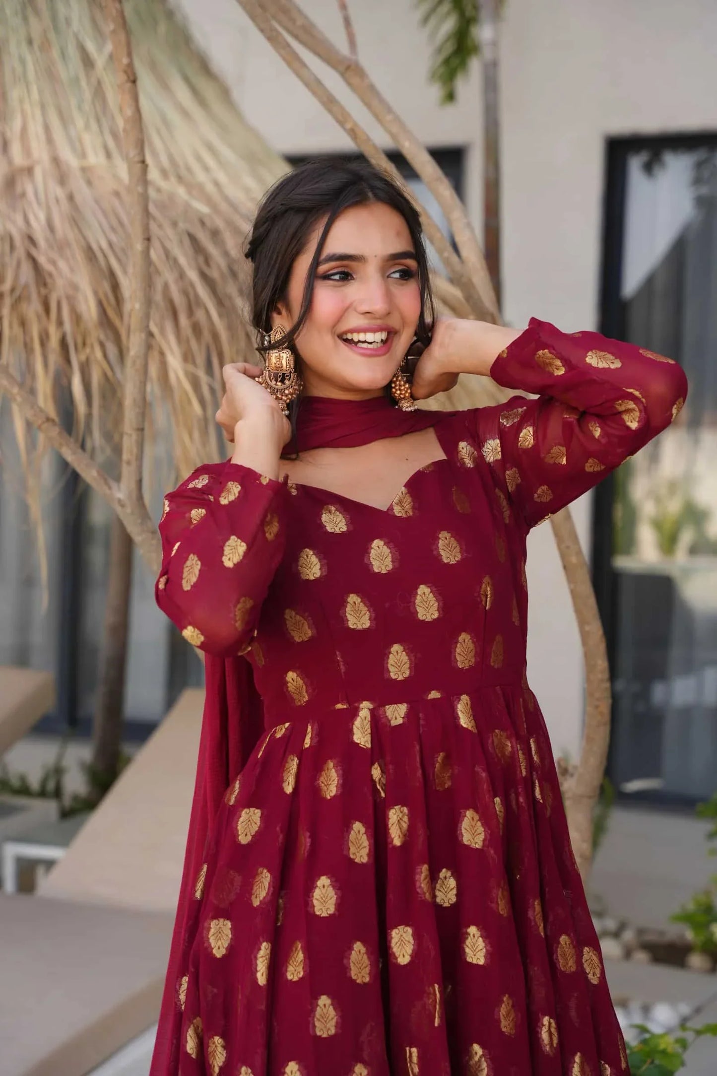 Woman wearing a maroon dress with gold patterns outdoors