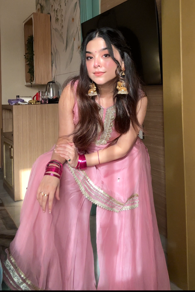 Woman in a pink traditional outfit with jewelry in an indoor setting