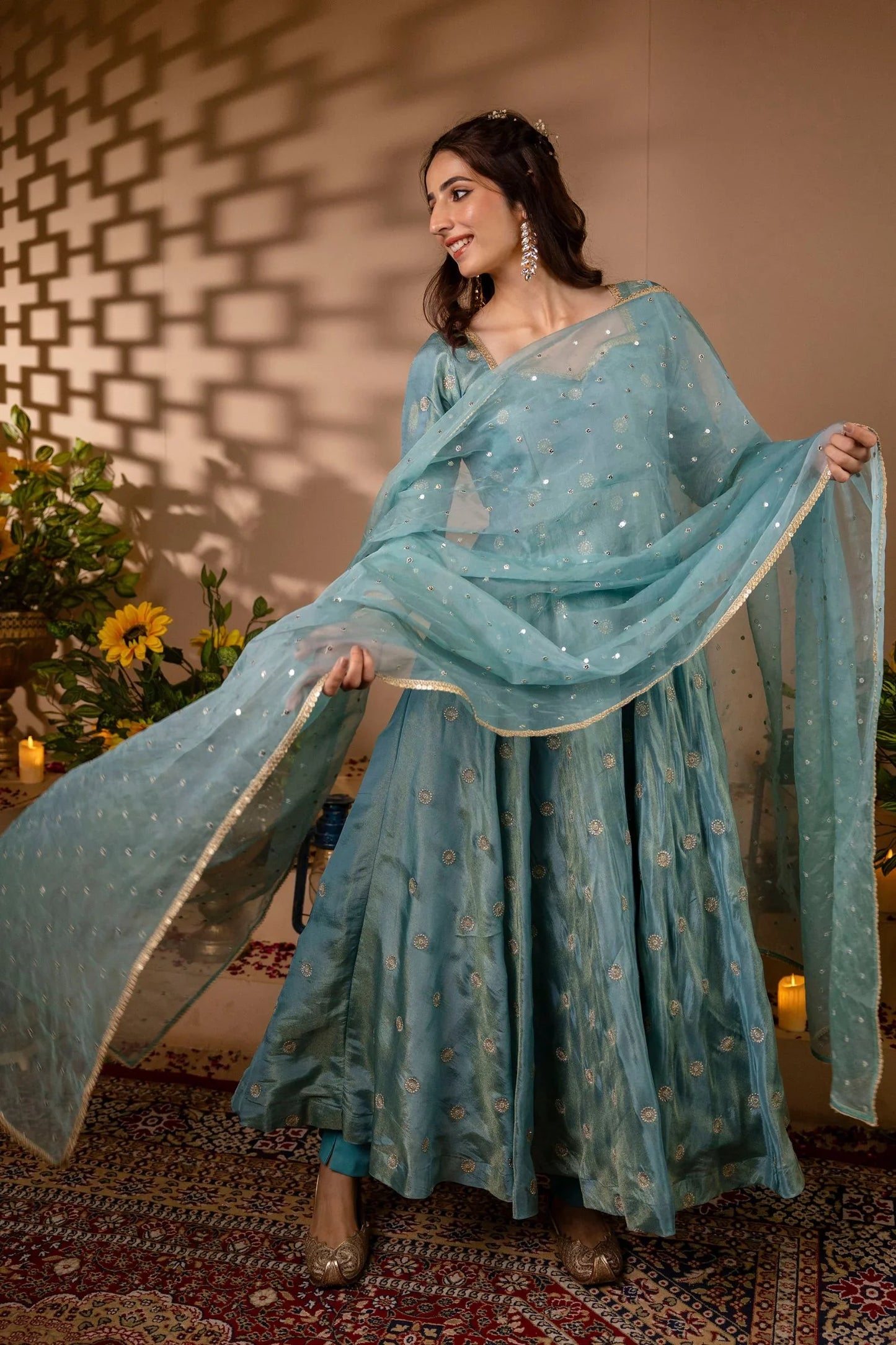 Woman in a light blue traditional outfit with a matching dupatta, standing indoors.
