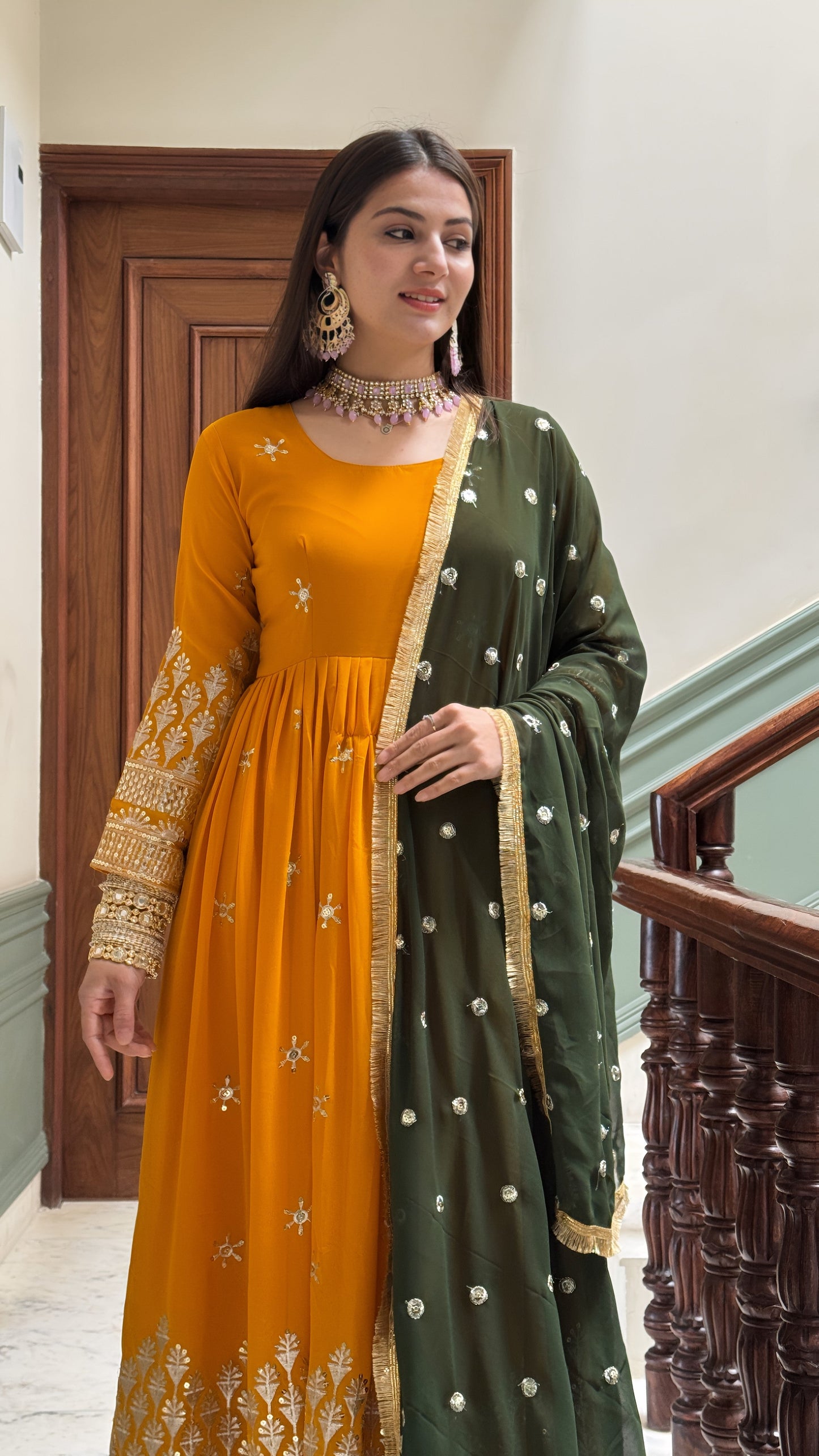 Woman wearing a mustard yellow dress with green dupatta indoors.