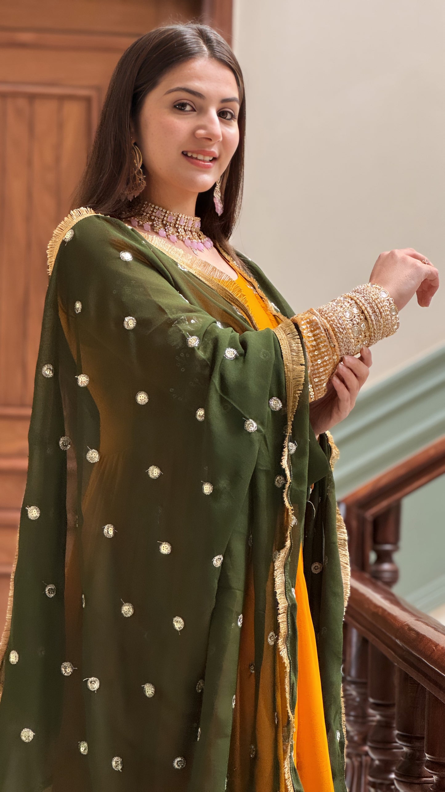 Woman wearing a green and gold traditional outfit with a polka dot pattern.