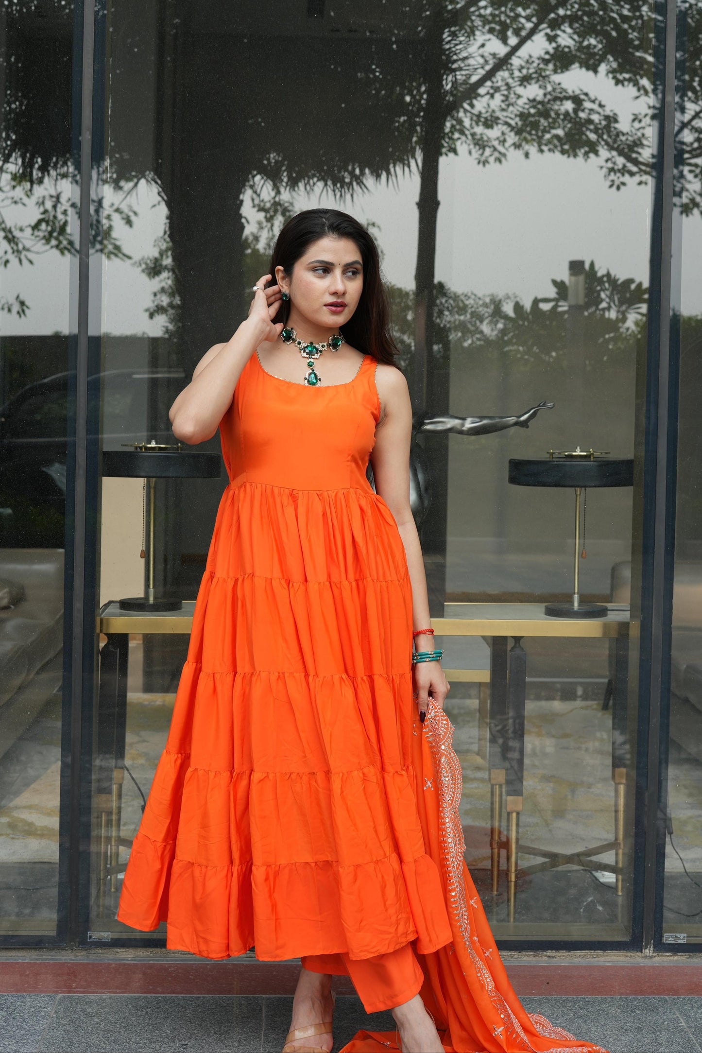 Woman in an orange dress standing in front of a glass door.