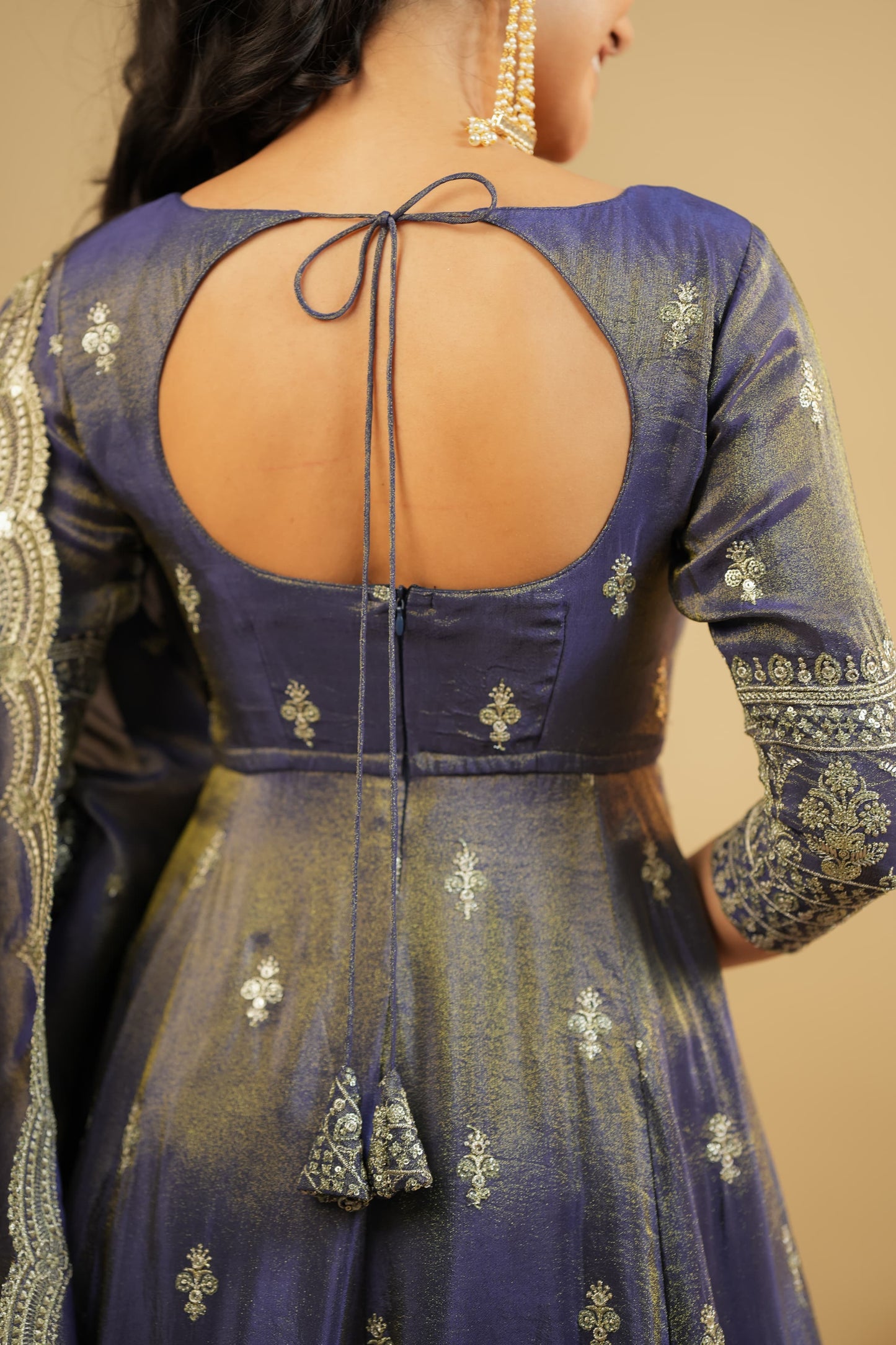Navy blue embroidered traditional outfit with open back on a beige background