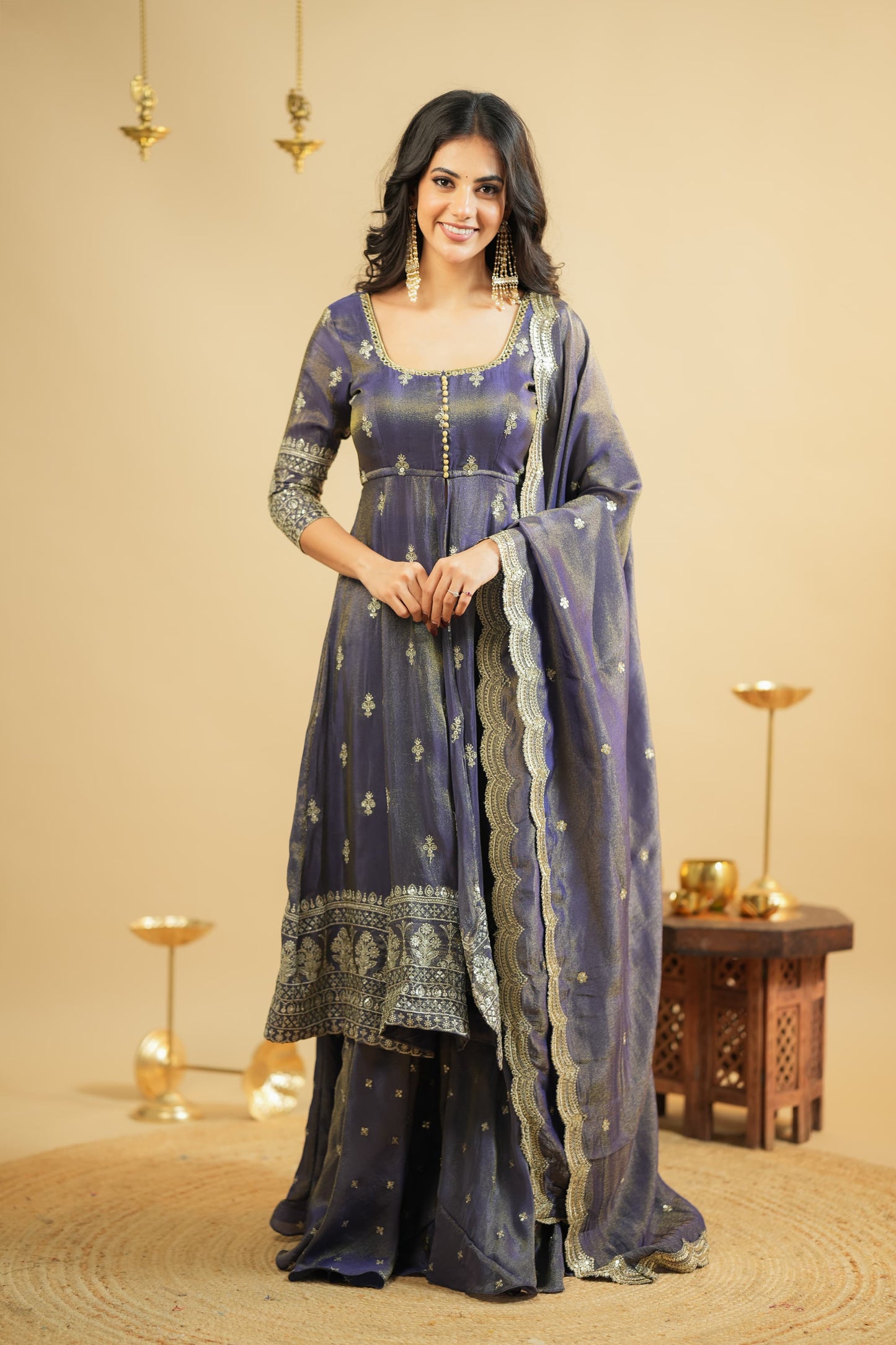 Woman in a traditional outfit with a blue and silver patterned dress against a beige background