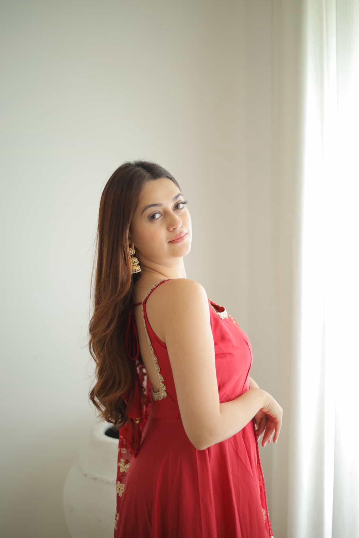 Woman in a red dress standing against a neutral background