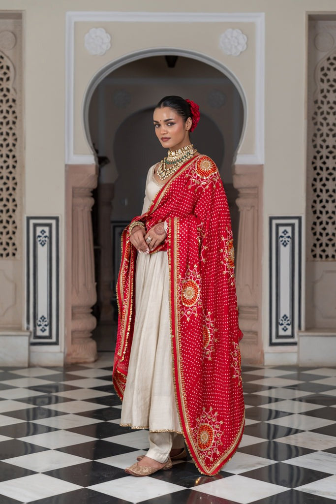 Woman in traditional attire with a red and gold shawl in an ornate architectural setting