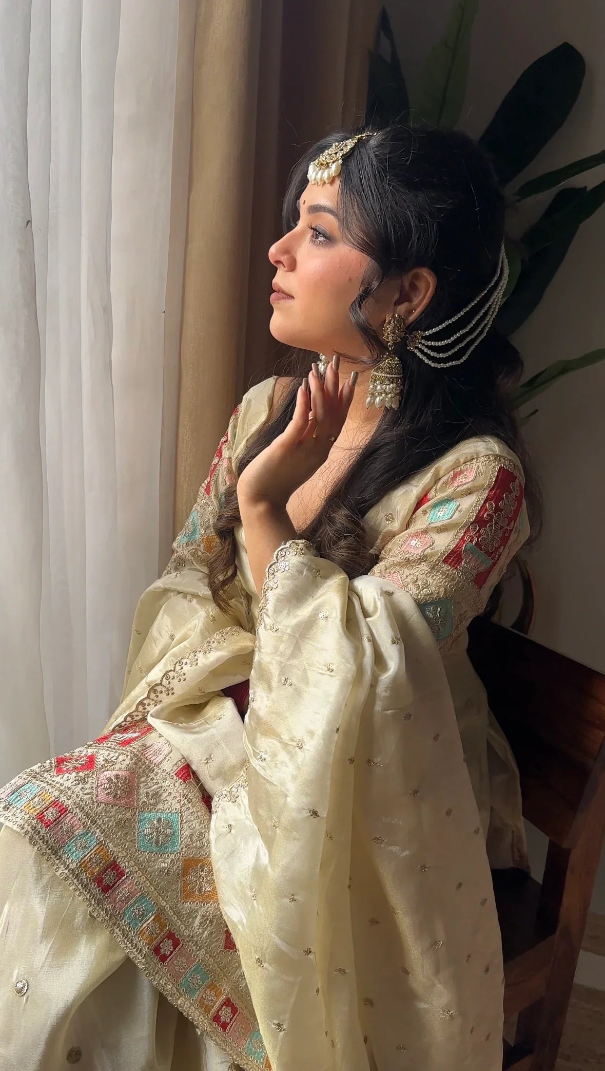 Woman in traditional attire sitting indoors with a neutral background