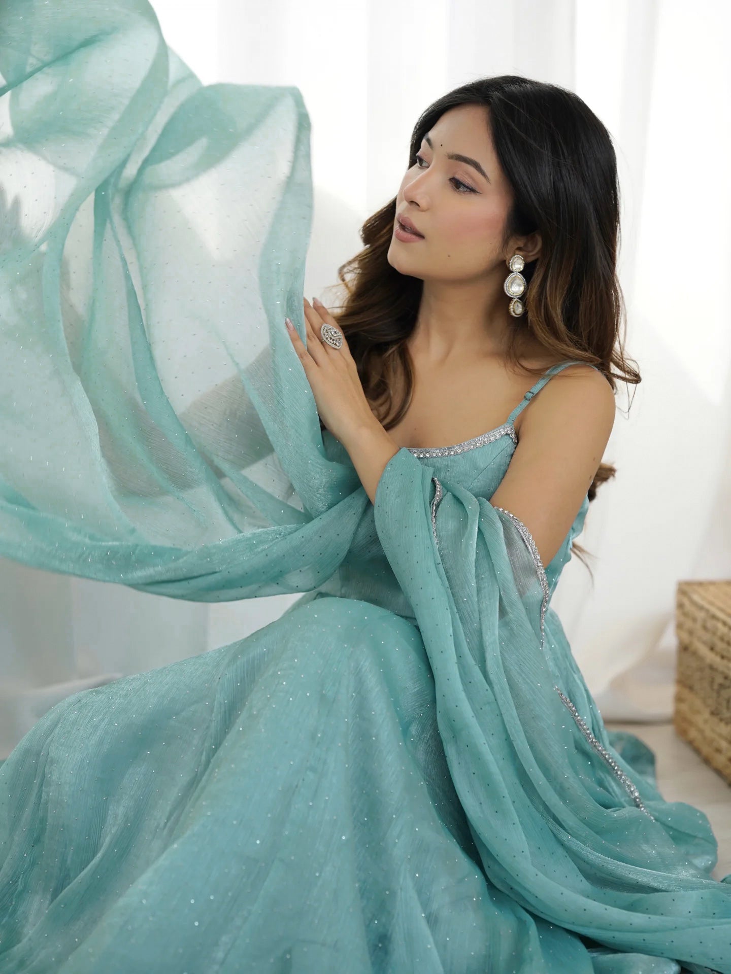 Woman in a light blue dress with a flowing fabric against a white background