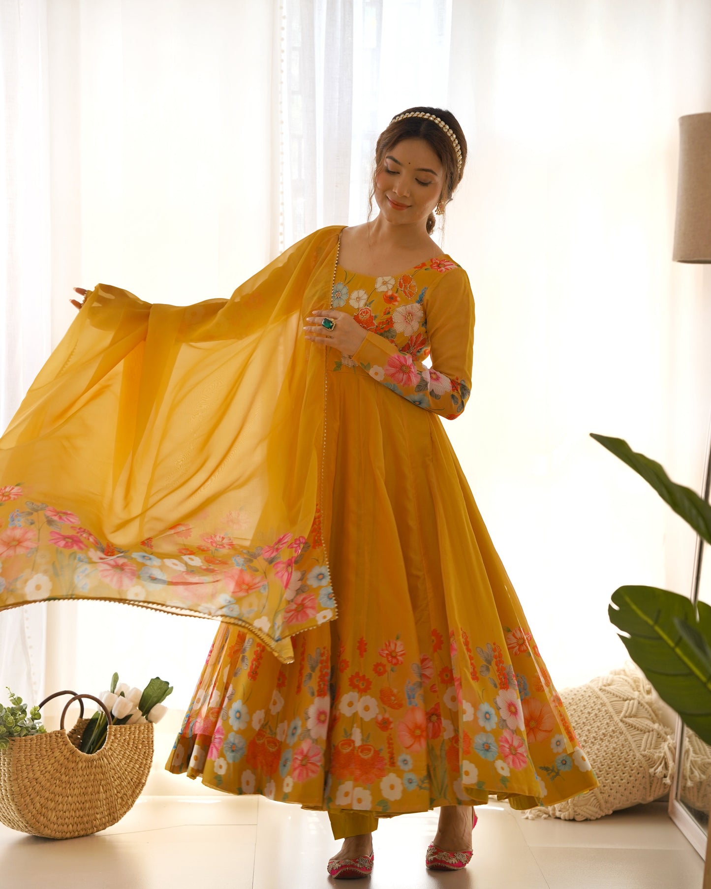 Woman in a yellow floral dress standing in a bright room with white curtains.