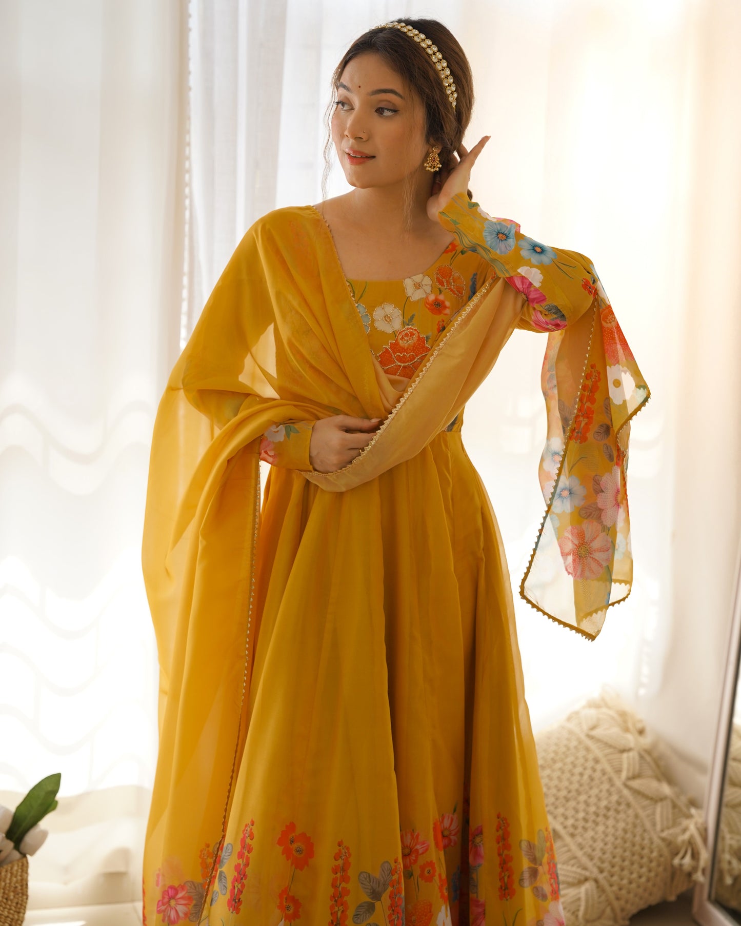 Woman wearing a yellow traditional outfit with floral patterns indoors.