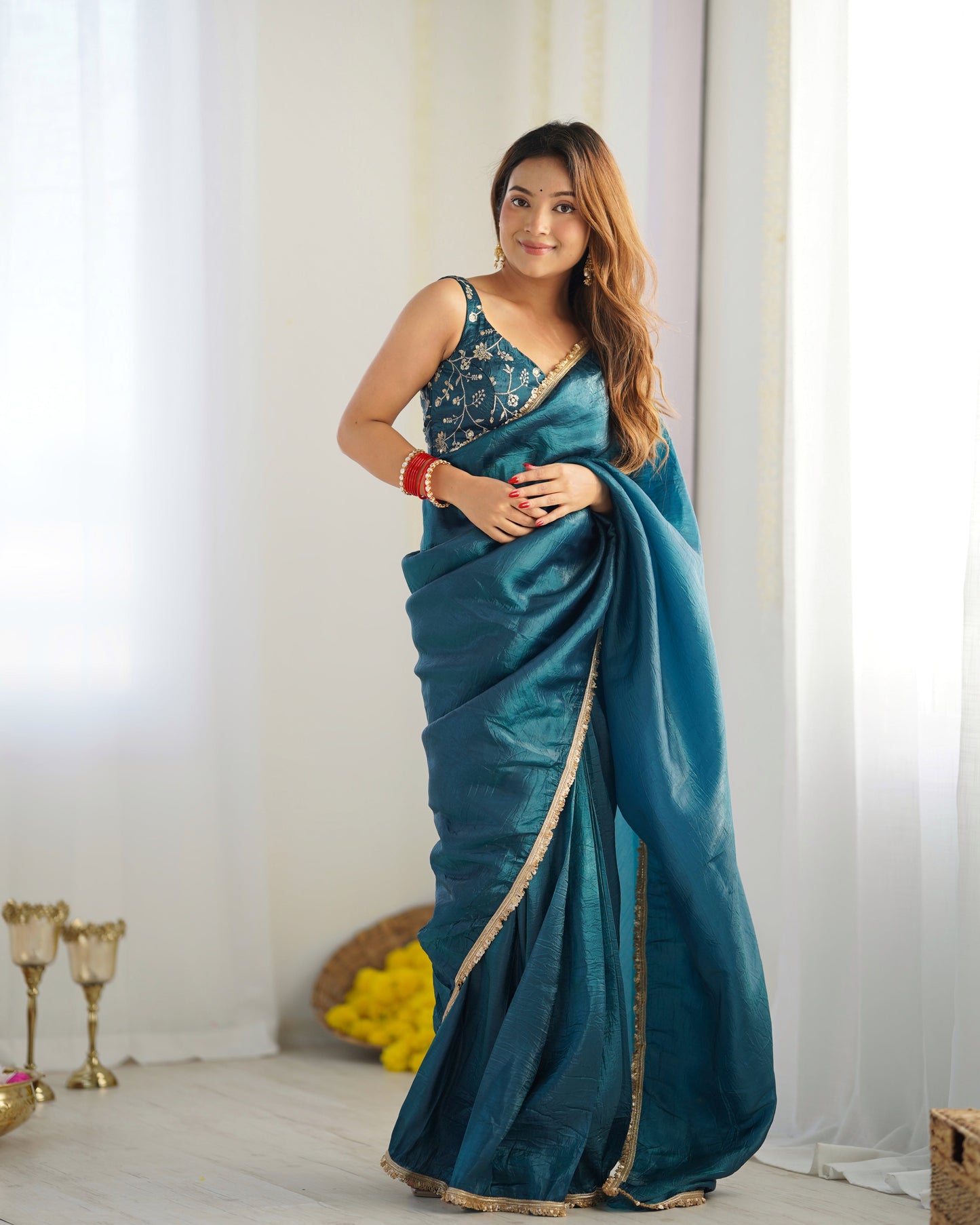 Woman wearing a blue saree with a white curtain background