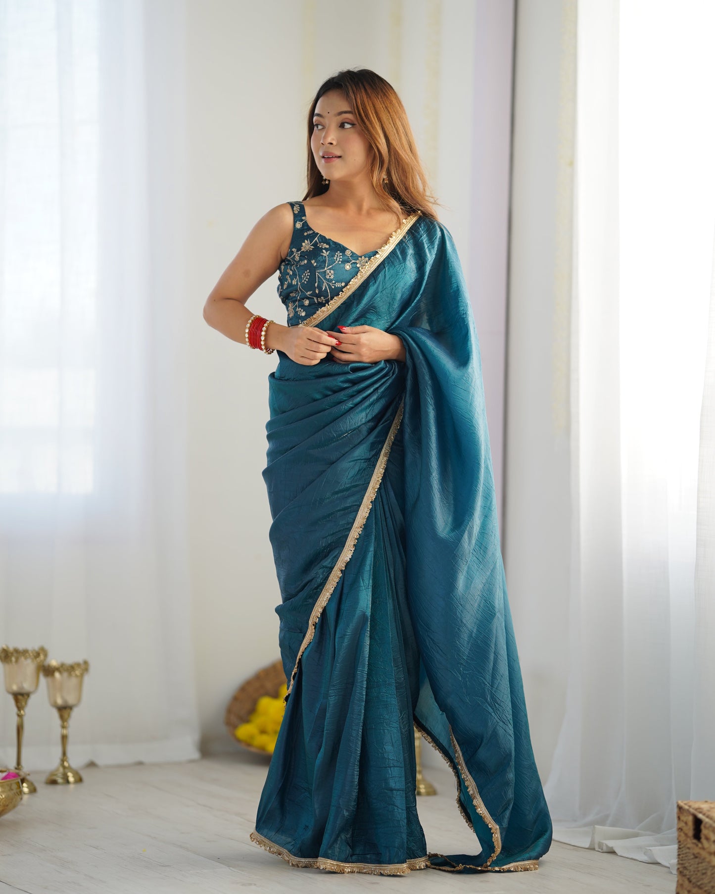 Woman wearing a teal saree with a white background