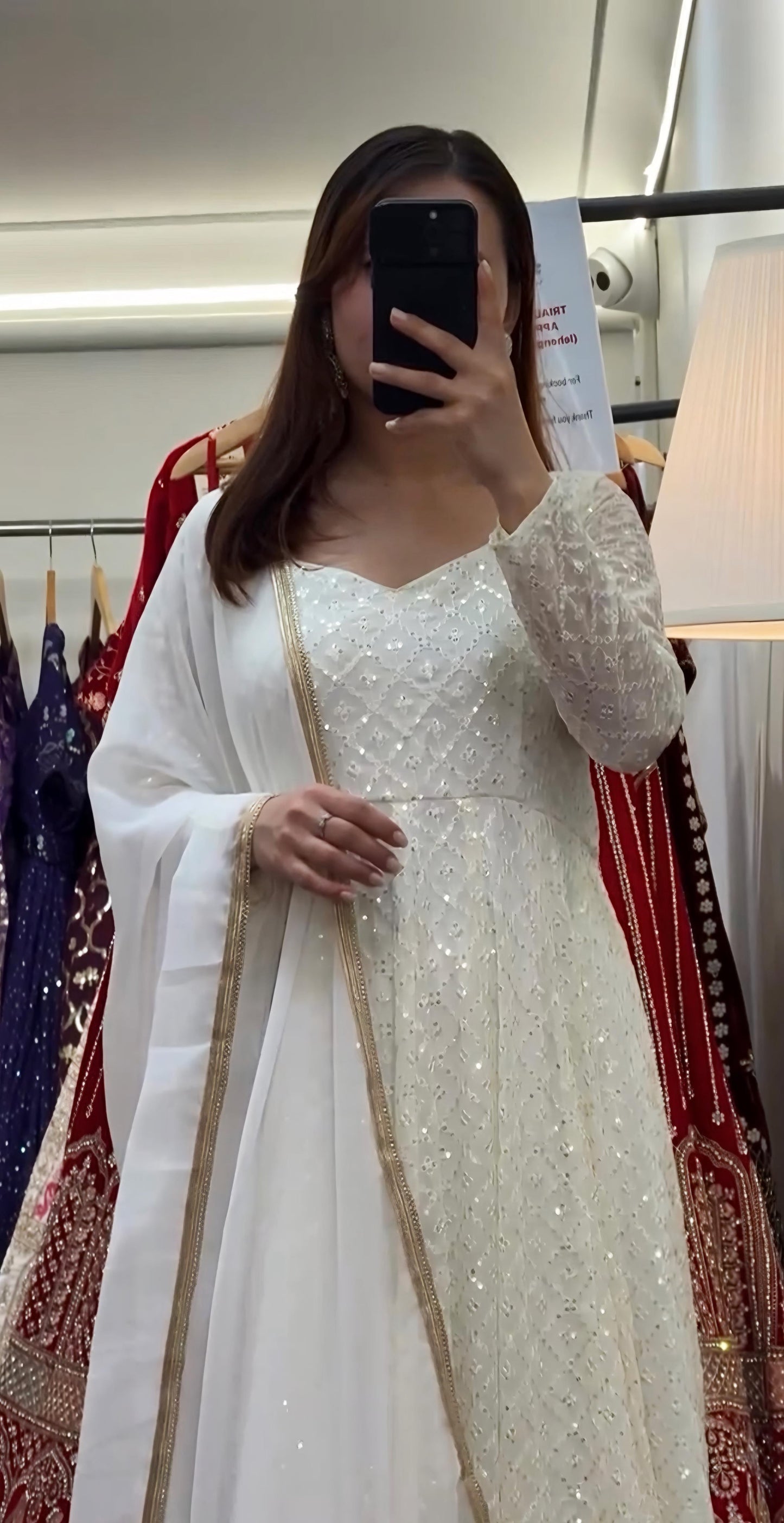 Woman wearing a white and gold traditional outfit in a store setting.