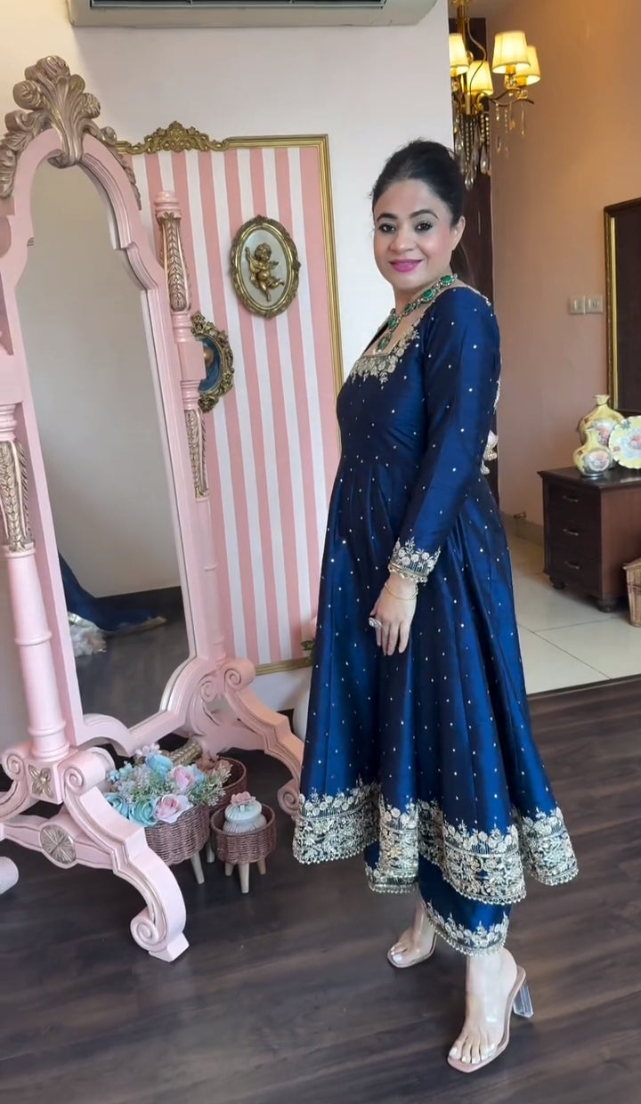 Woman in a blue traditional outfit standing in a room with decorative elements.