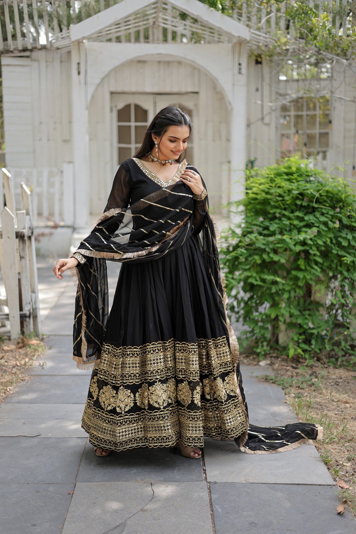 Woman in a black and gold traditional outfit standing outdoors.