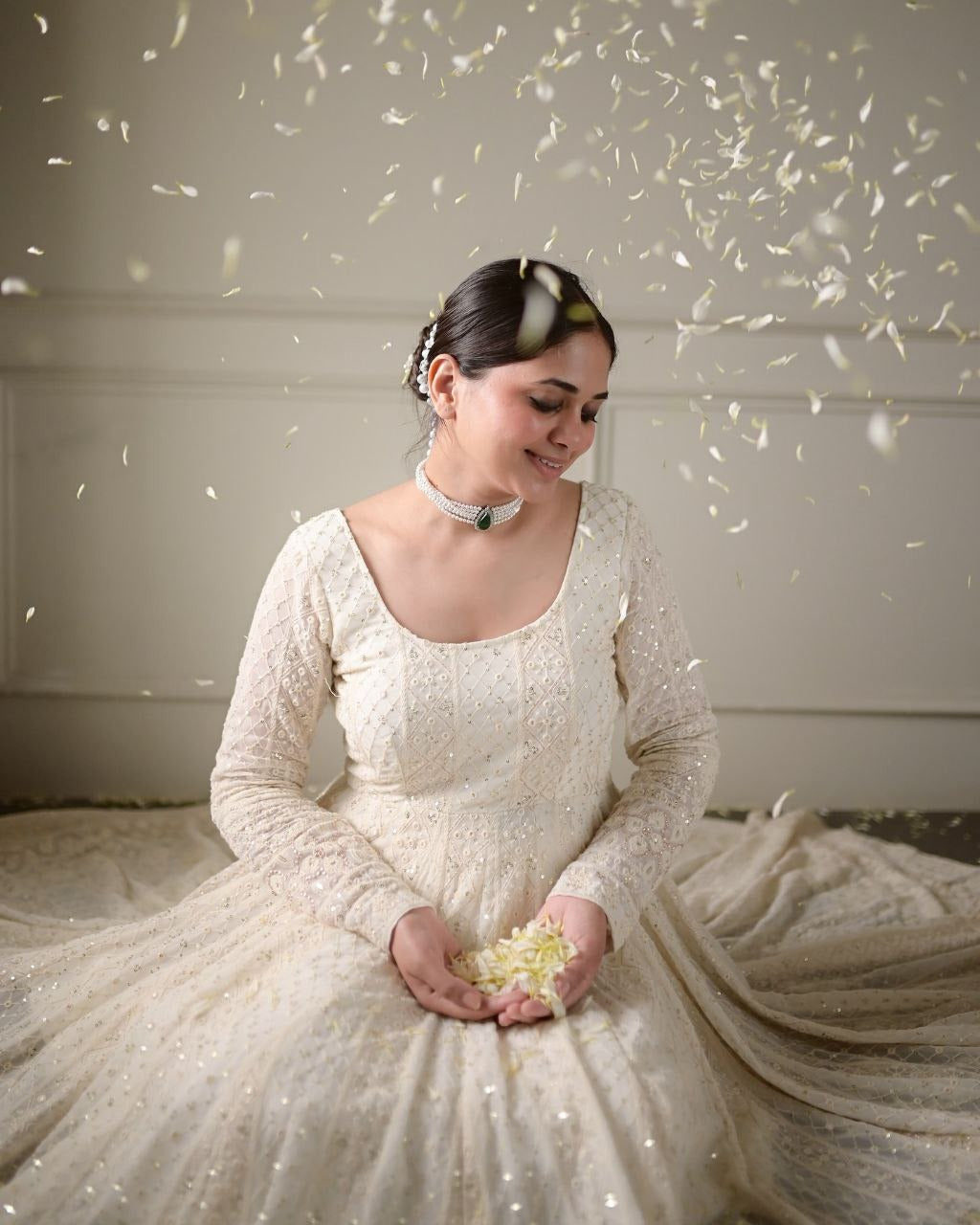 Woman in a white lace dress holding flowers with decorative elements in the background