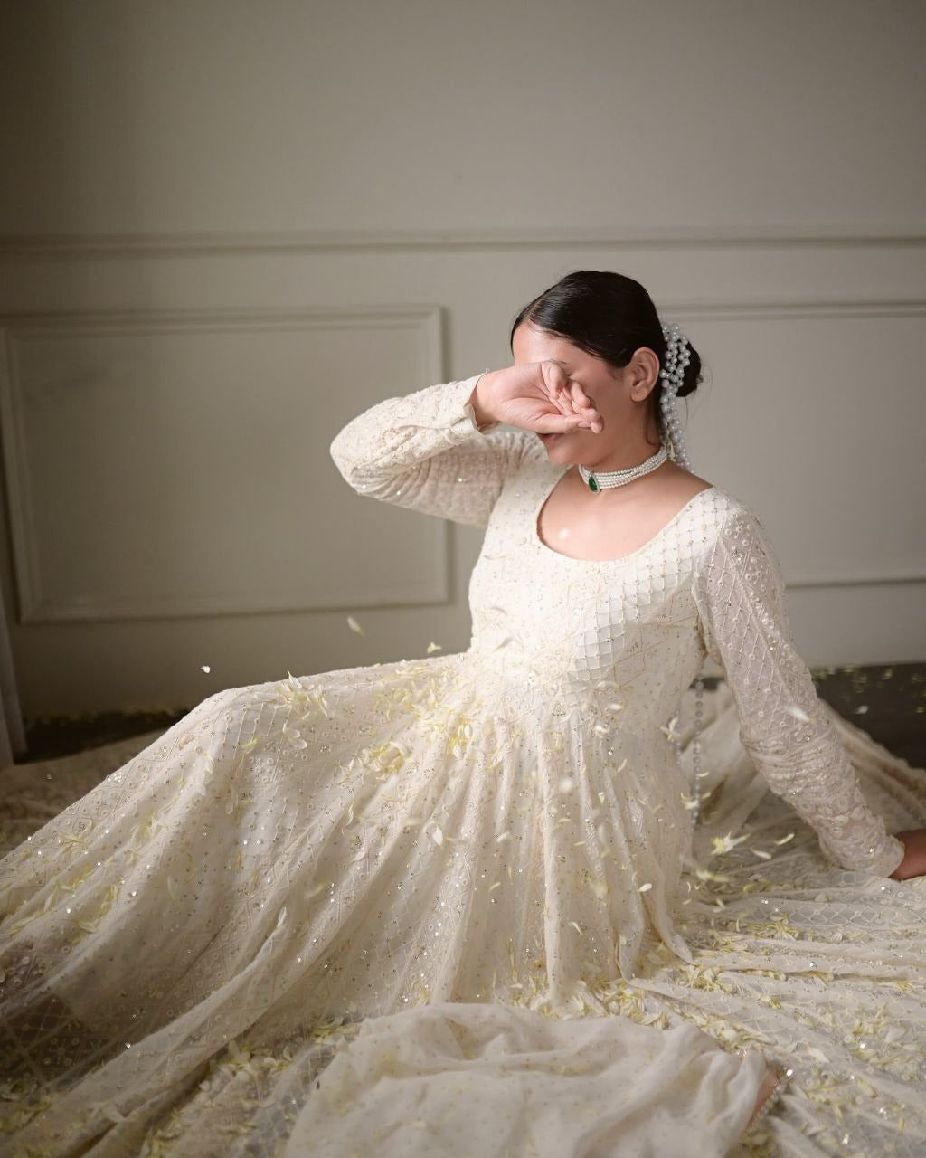 Woman in a white dress with long sleeves sitting on the floor.