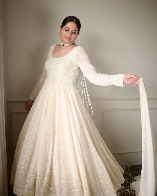 Woman wearing a white embroidered gown with long sleeves and a matching shawl.