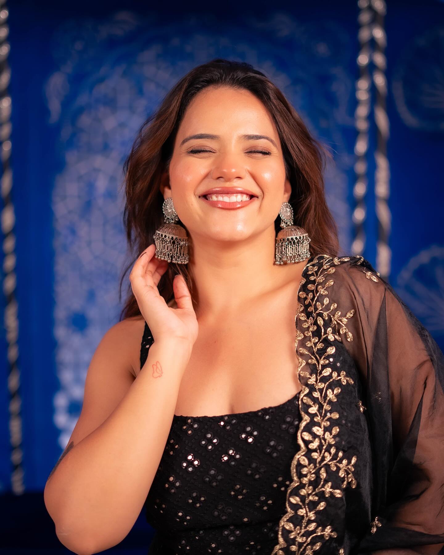 Woman wearing large earrings against a blue patterned background