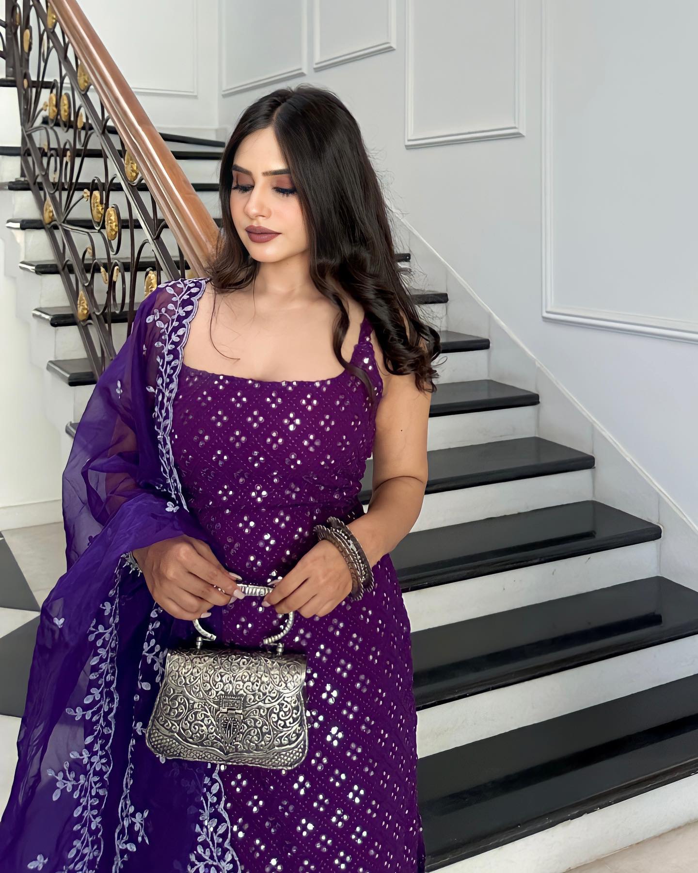 Woman in a purple dress holding a silver handbag on a staircase