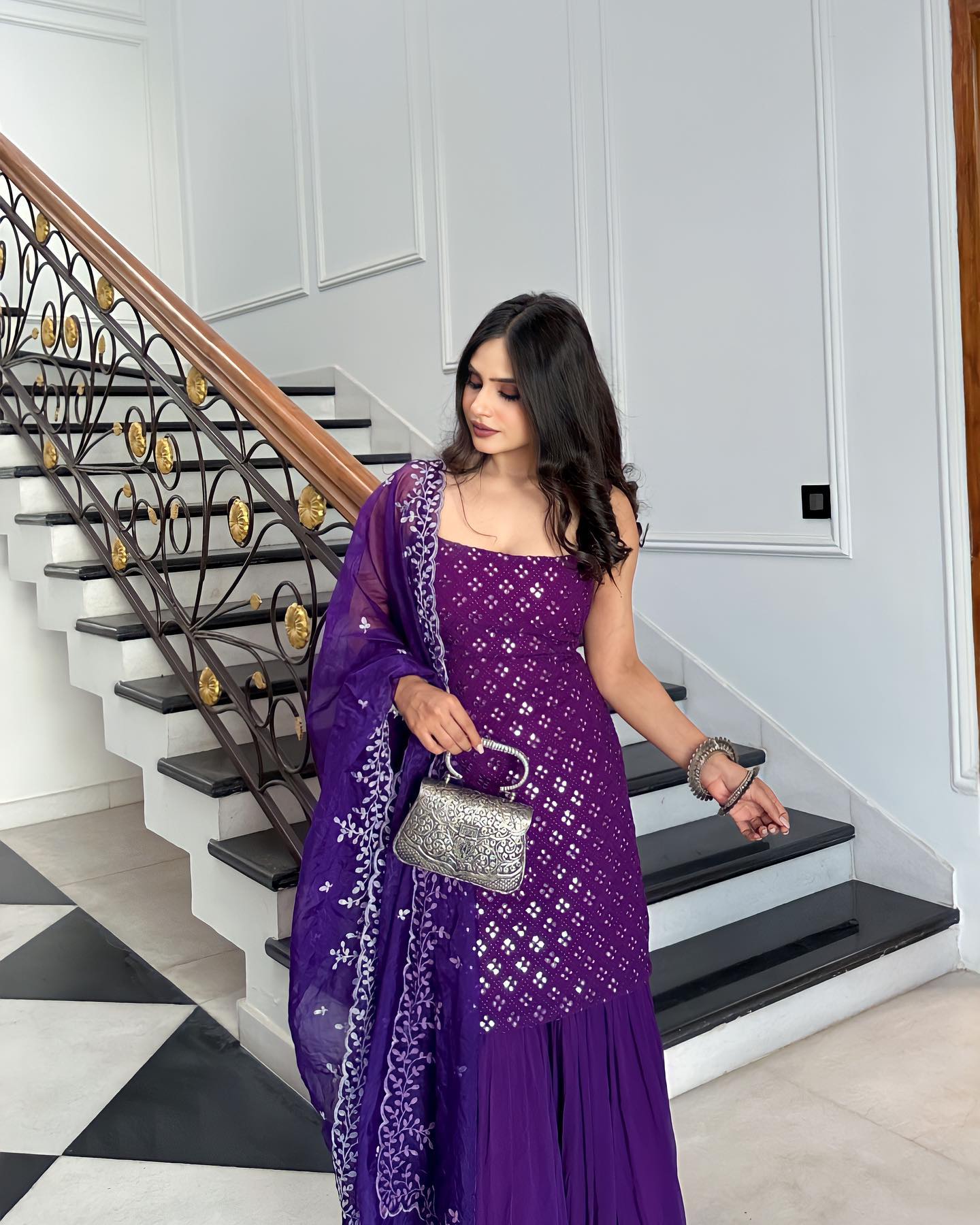 Woman in a purple dress standing on a staircase in a home setting