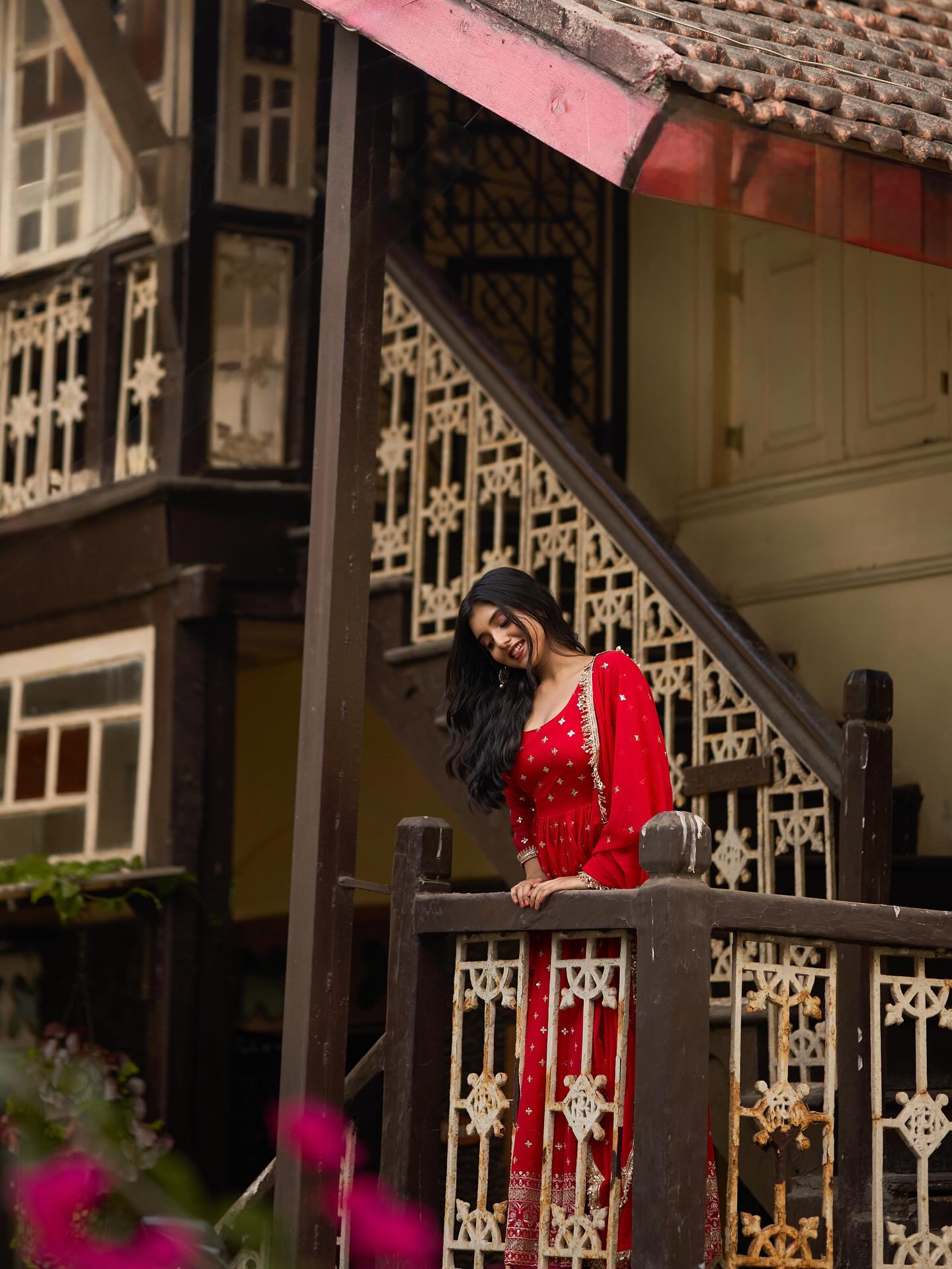 Woman in a red dress standing on a balcony of a traditional building