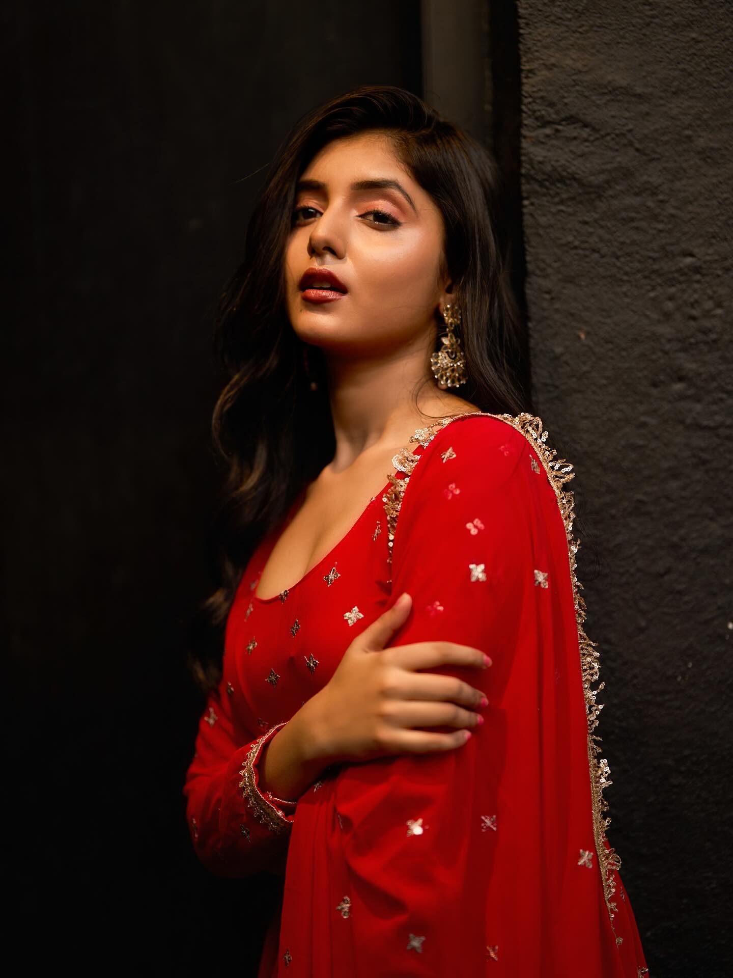 Woman in a red traditional outfit with gold details against a dark background