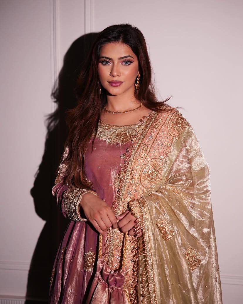 Woman wearing a traditional embroidered outfit with a plain background