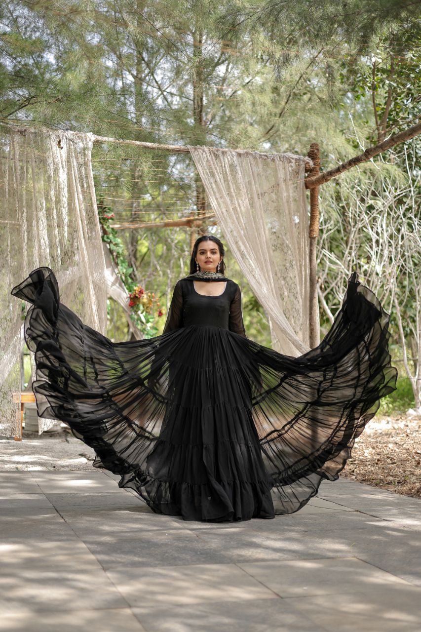 Woman in a long black dress with a flowing skirt standing outdoors.