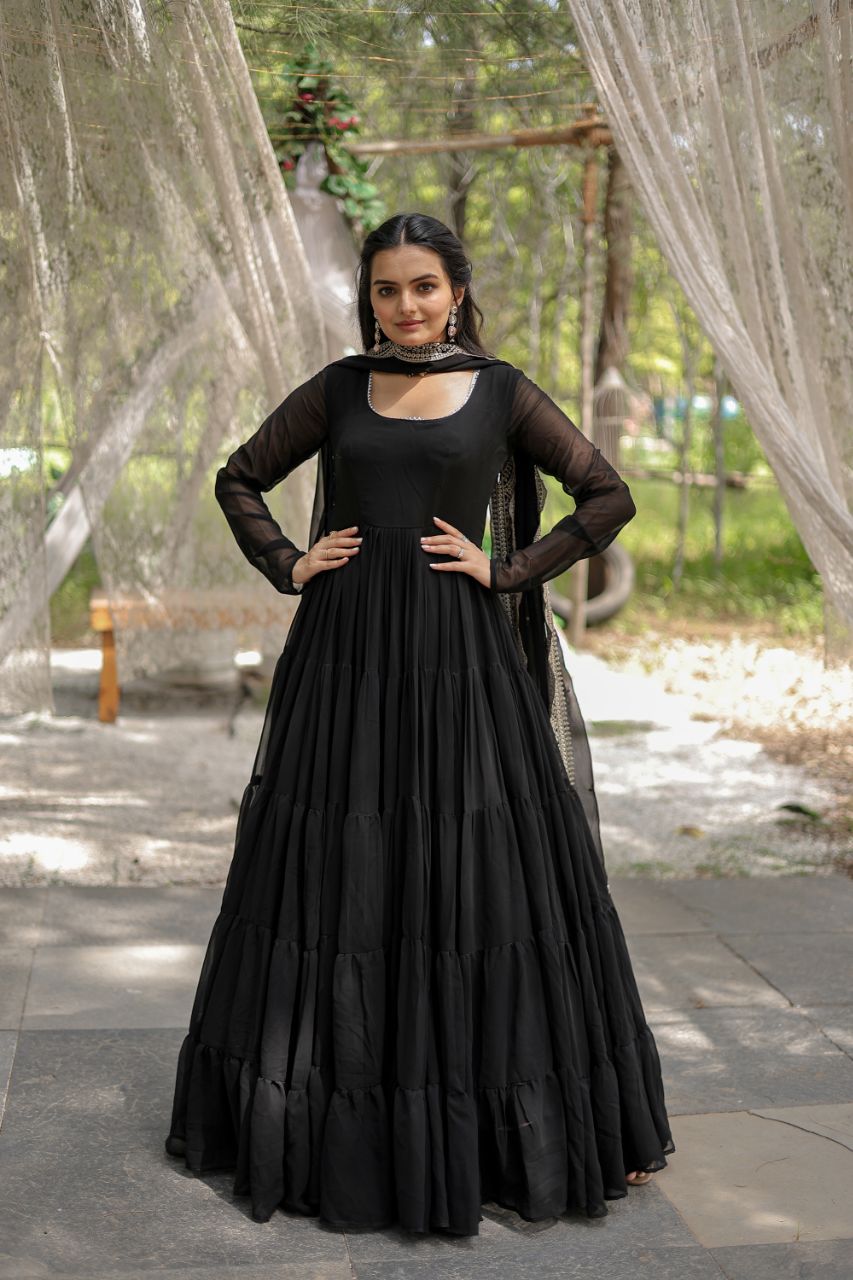 Woman in a black dress standing outdoors with greenery in the background