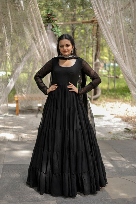 Woman in a black dress standing outdoors with greenery in the background