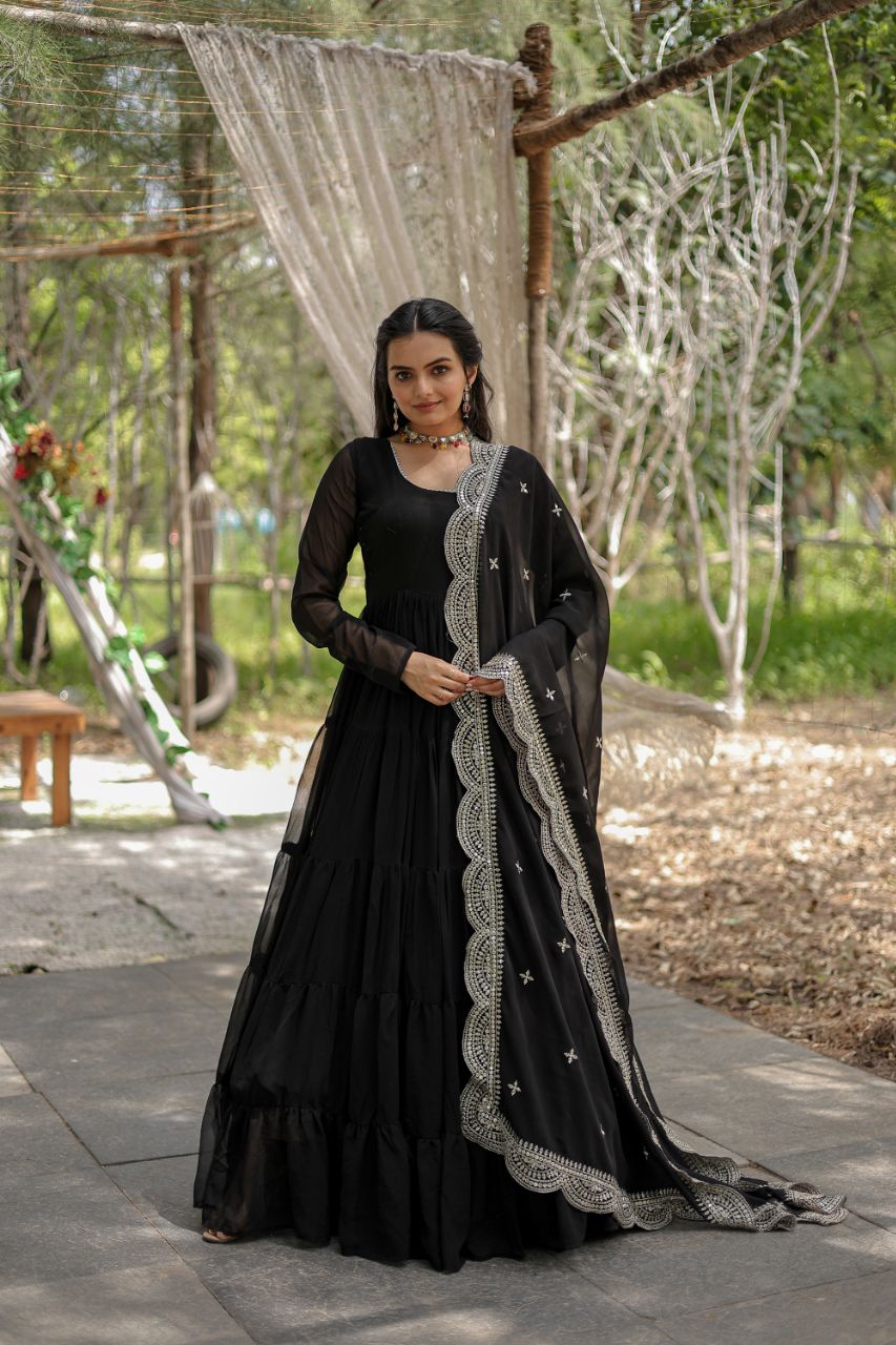 Woman in a black traditional outfit with a decorative shawl standing outdoors.