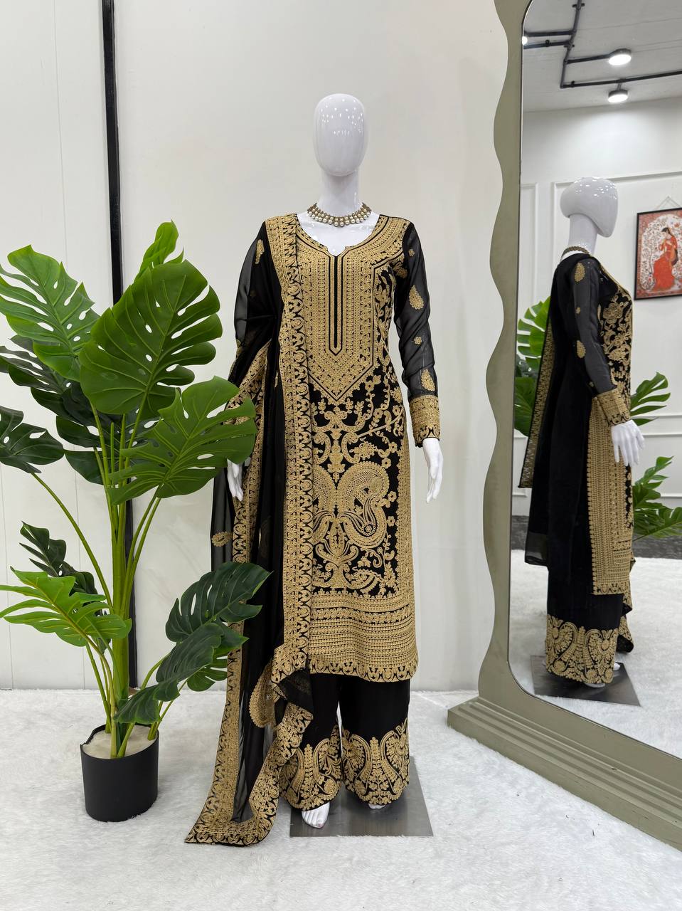 Mannequin wearing a black and gold embroidered outfit with a mirror reflection in a store setting.