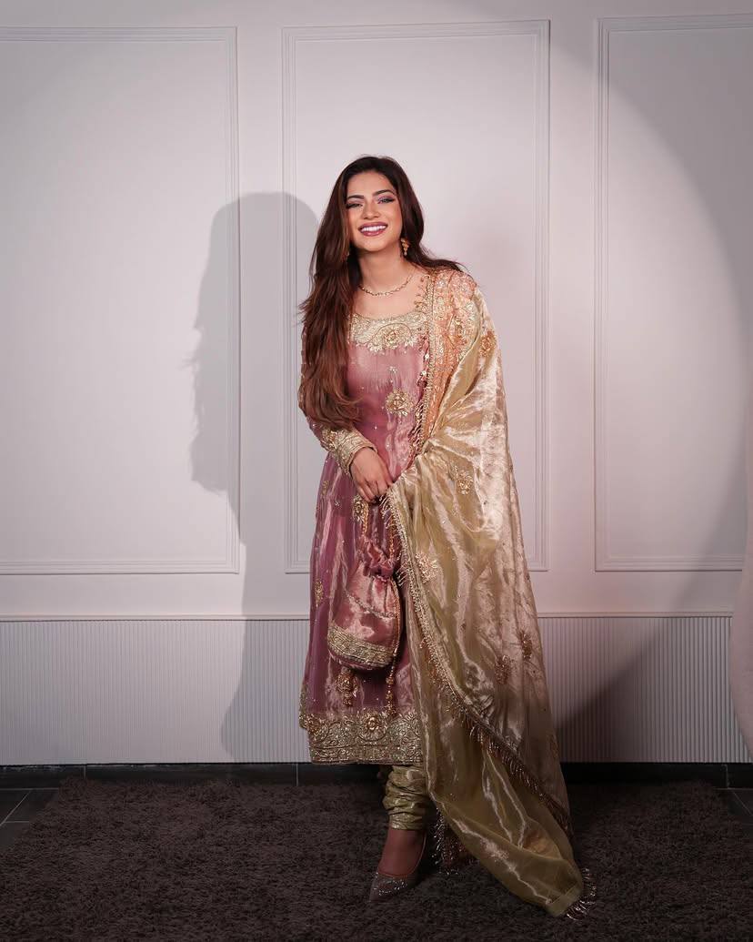 Woman in a traditional outfit standing against a white wall