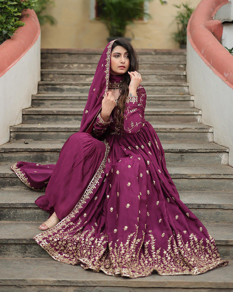 Woman in a purple traditional outfit with gold embroidery sitting on steps.