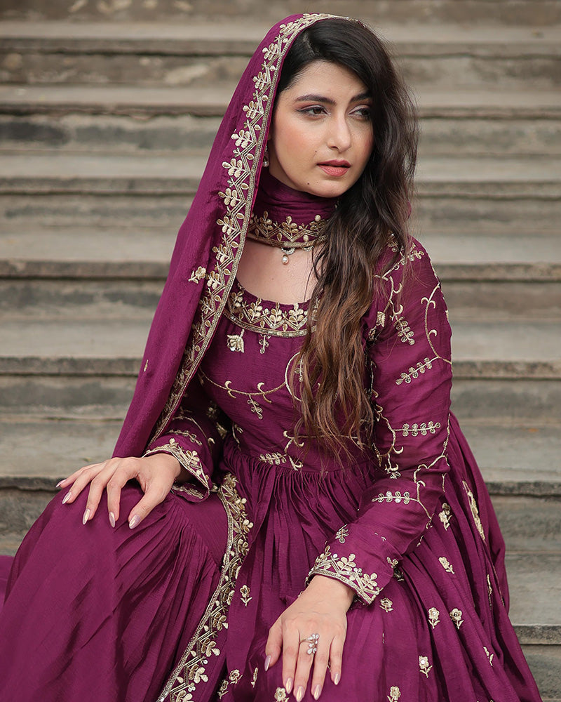 Woman in a purple embroidered traditional outfit sitting on steps.