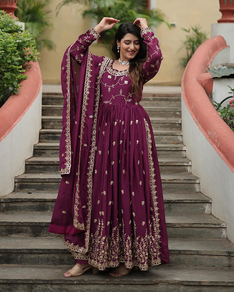 Woman in a purple embroidered traditional outfit standing on steps outdoors.