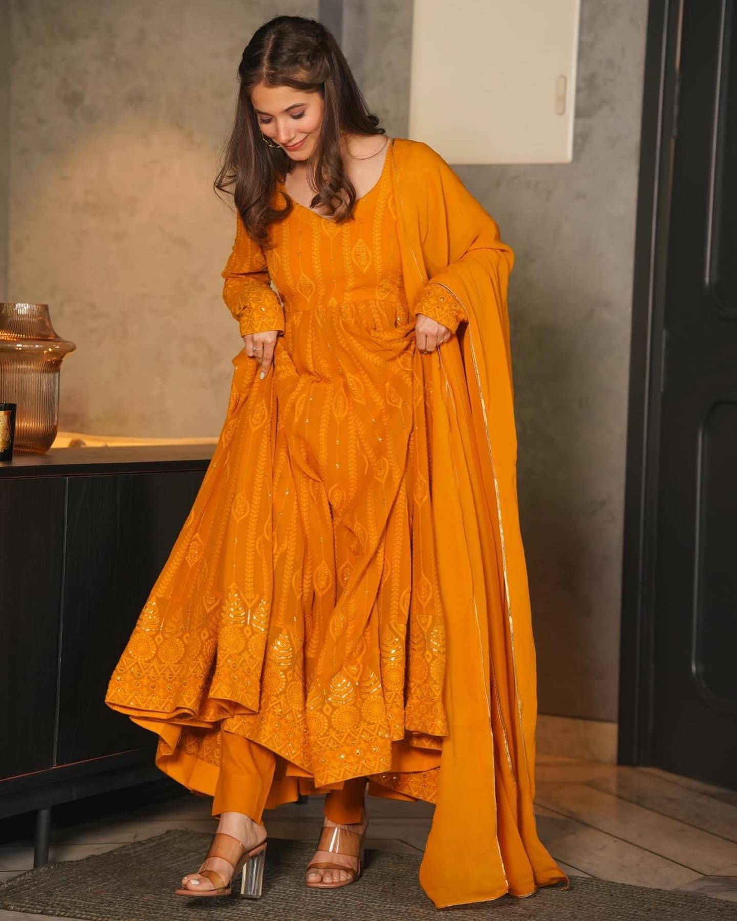 Woman wearing a mustard yellow traditional outfit indoors.