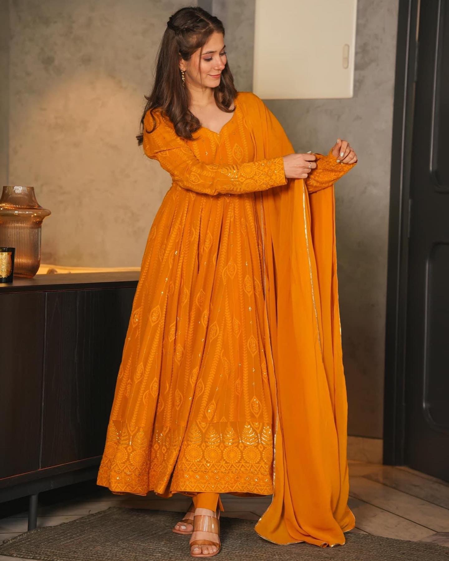 Woman wearing a mustard yellow embroidered dress indoors.