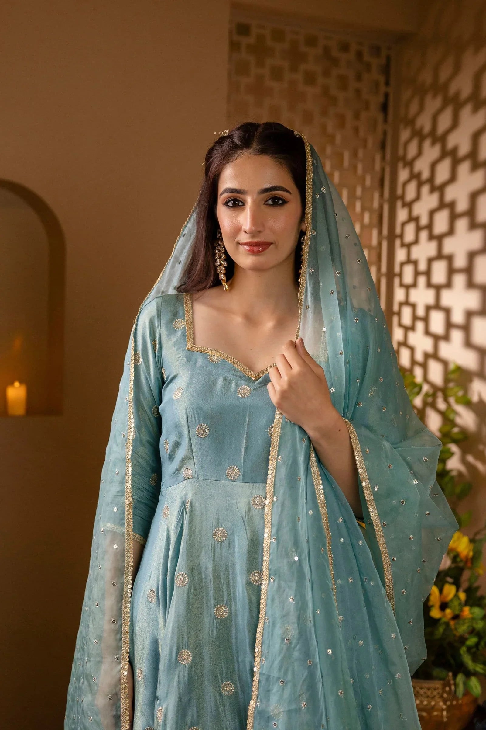 Woman in a light blue traditional outfit with a matching dupatta, standing indoors.