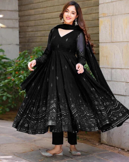 Woman wearing a black anarkali suit with intricate designs outdoors.