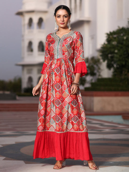Woman wearing a red patterned dress standing in front of a white building.