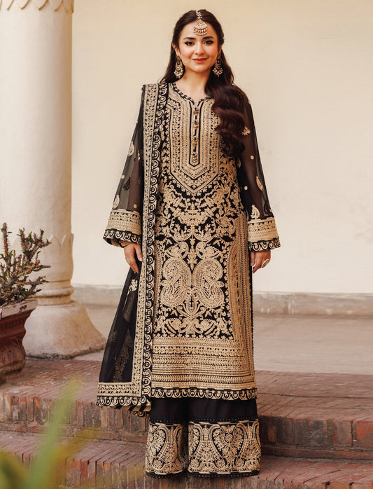 Woman wearing a black and gold embroidered traditional outfit in an outdoor setting.
