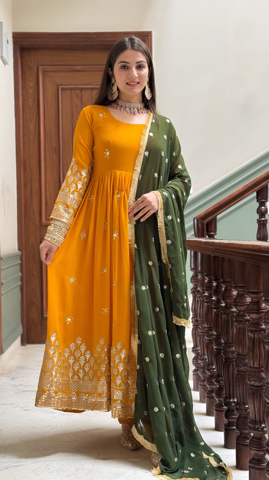 Woman wearing a yellow and green traditional outfit with embroidery, standing in a staircase.