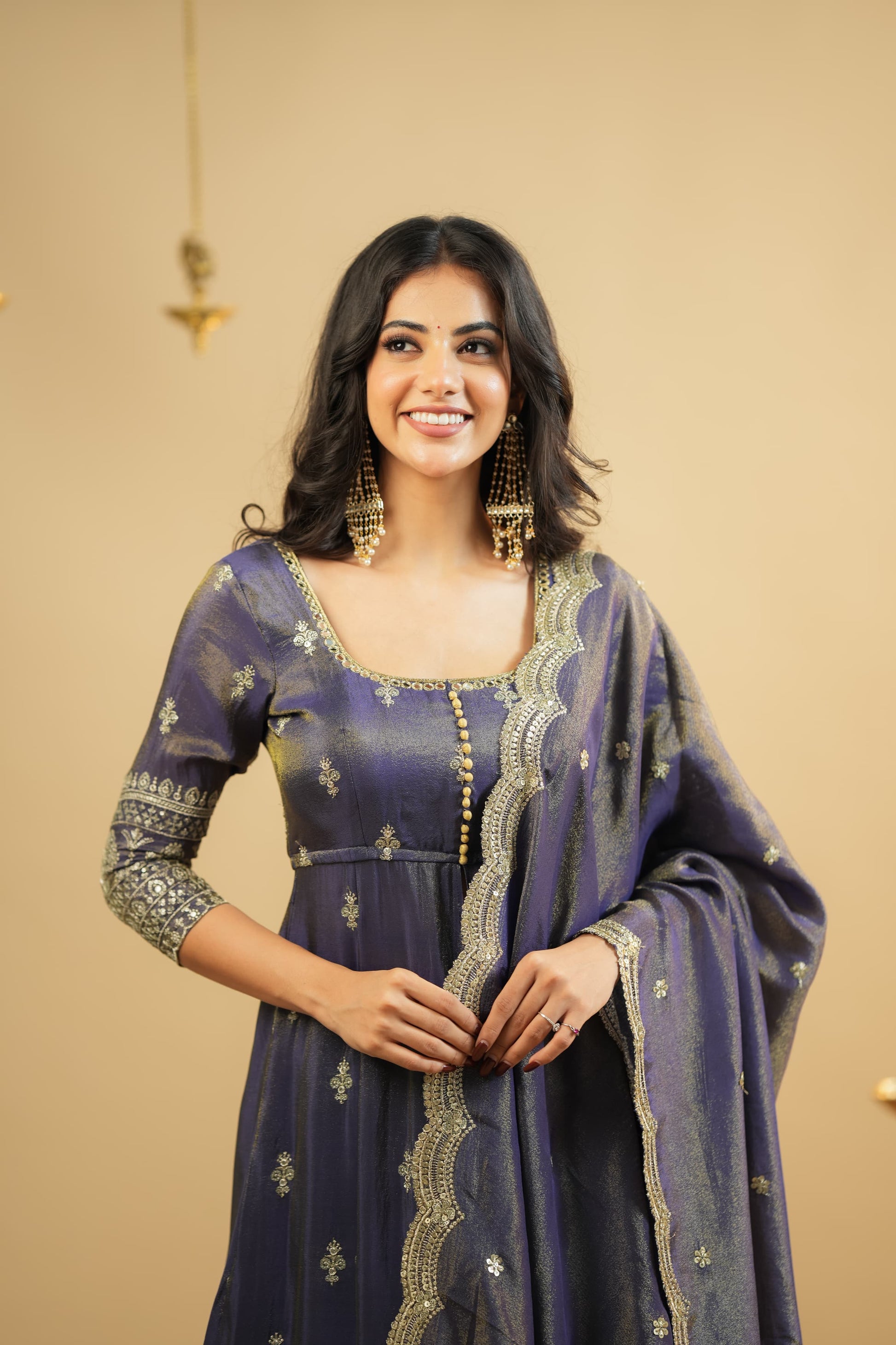 Woman wearing a traditional outfit with intricate designs on a beige background