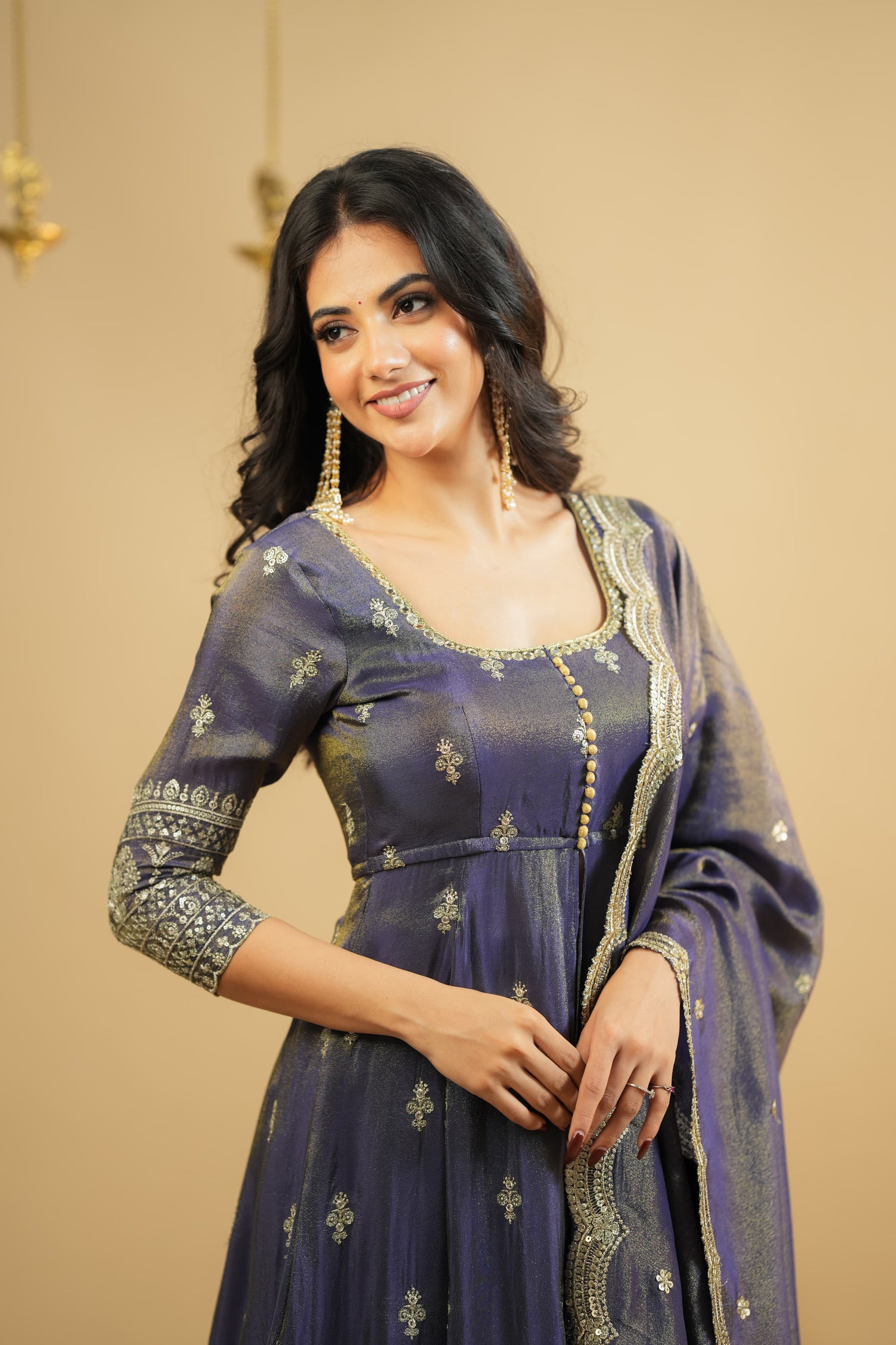 Woman wearing a traditional outfit with intricate designs on a beige background